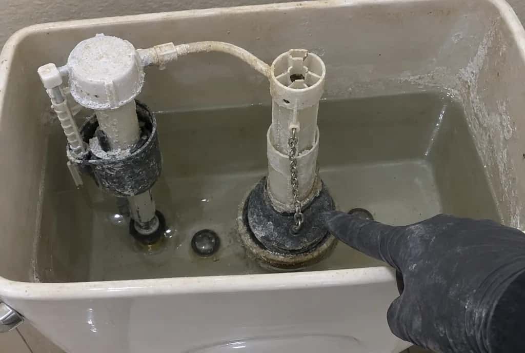 Interior de una cisterna con el grifo de llenado y la válvula de descarga cubiertos de cal