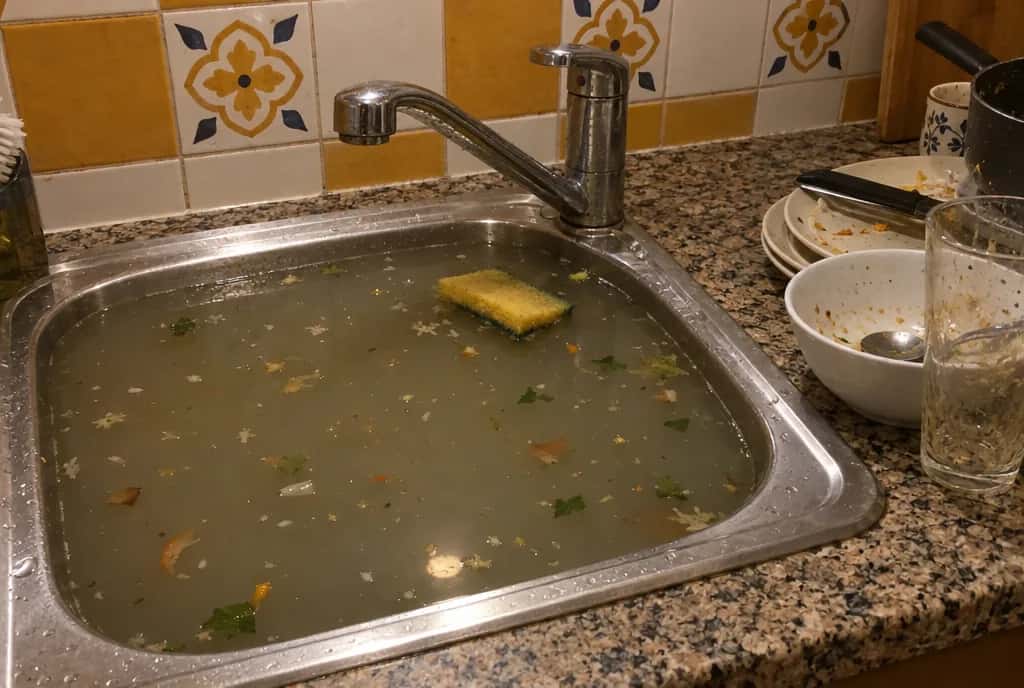 Fregadero de cocina atascado y lleno de agua sucia