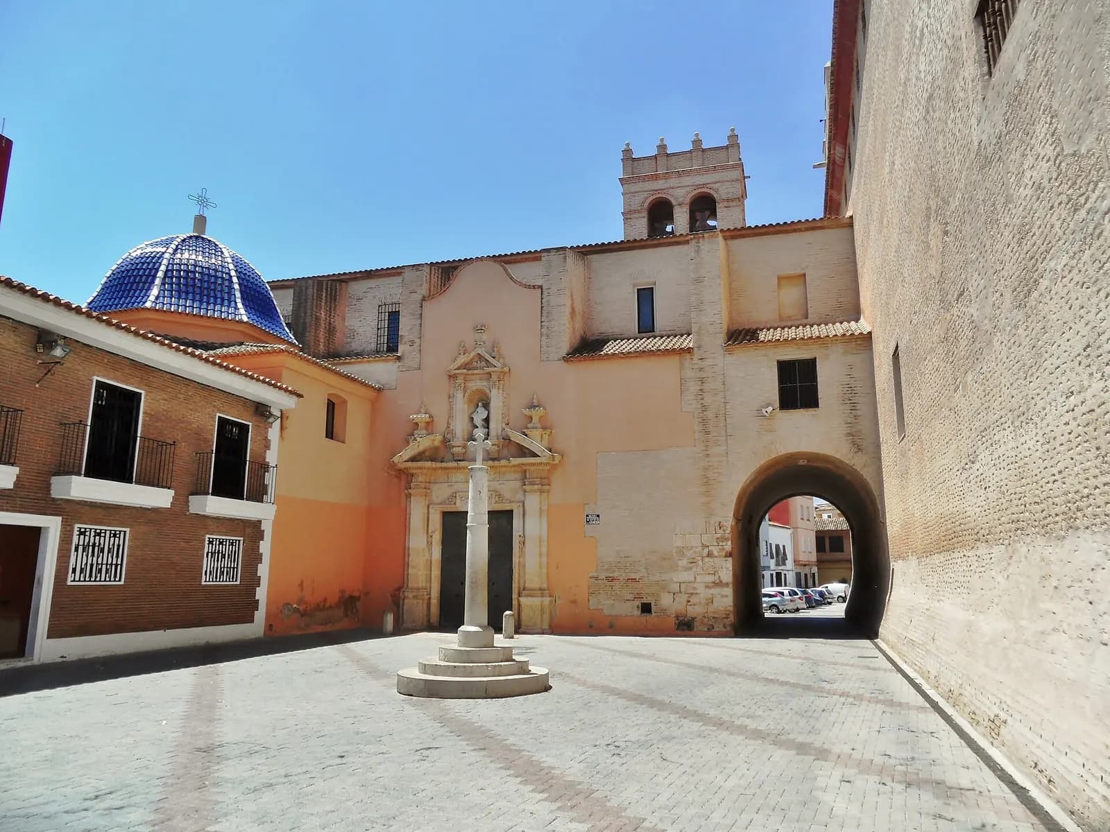 Castillo e iglesia de la Asunción de Alaquàs, con cúpula de teja azul y cruz de piedra en la plaza