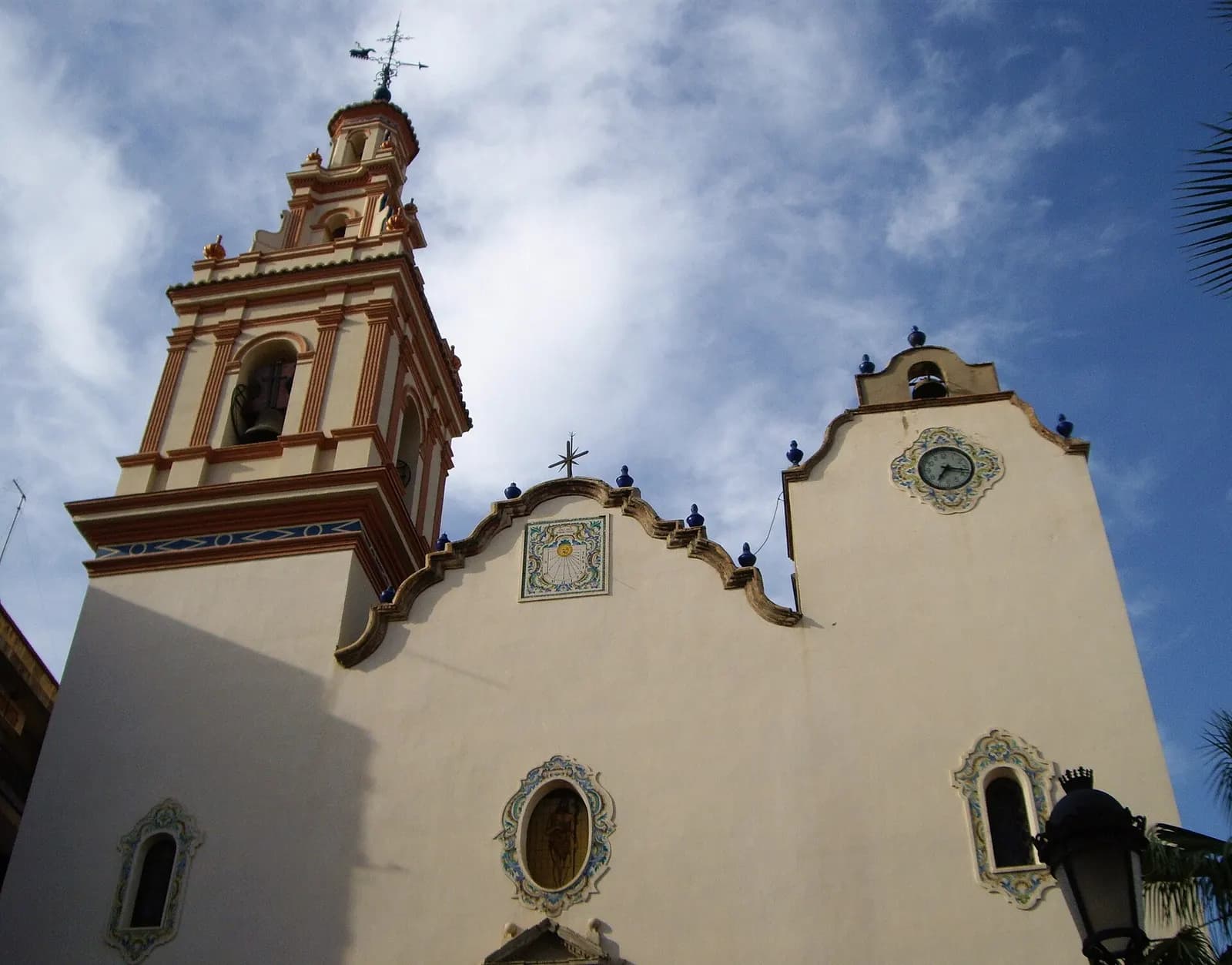 Iglesia de Sant Joan Baptista de Manises, con campanario de ladrillo y fachada encalada con reloj