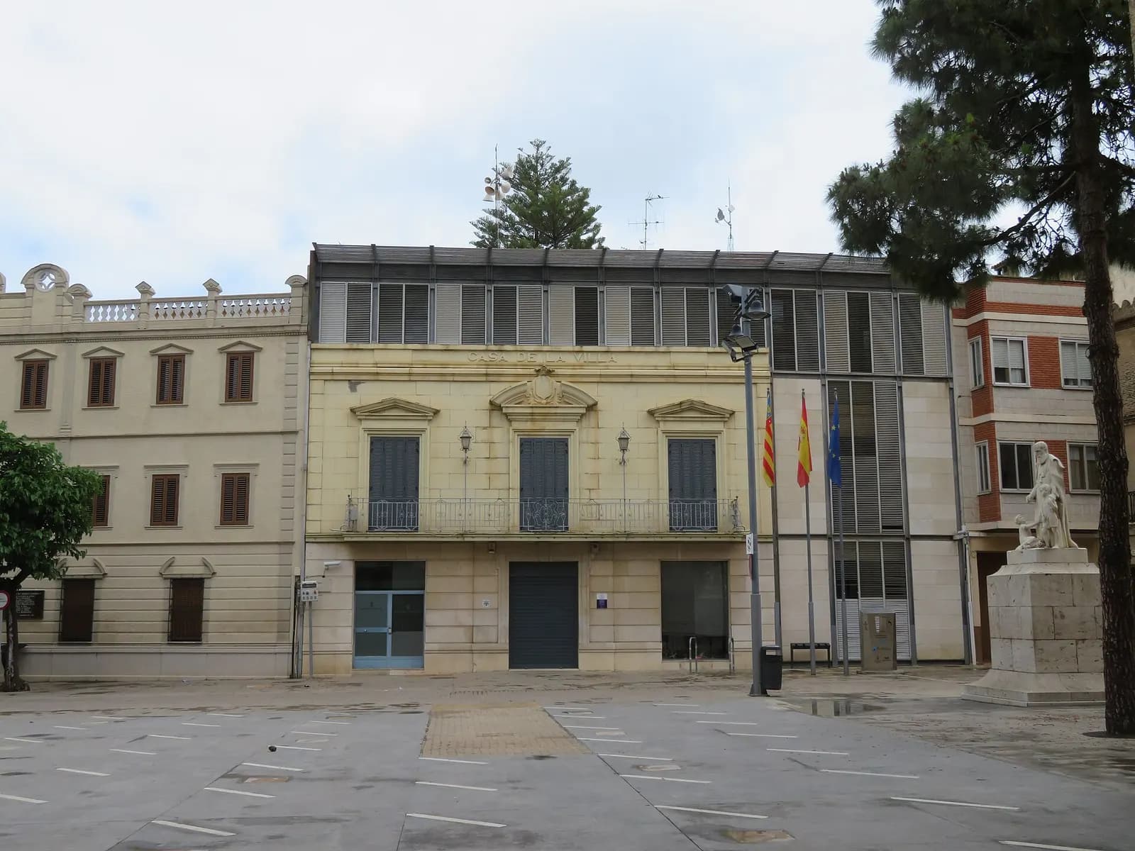 Ayuntamiento de Massamagrell frente a una plaza amplia con un monumento y pinos