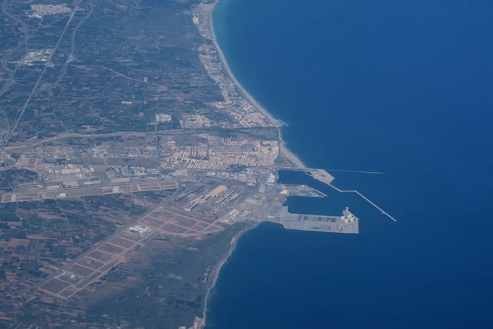 Vista aérea del Puerto de Sagunto con el casco urbano junto a la playa, los muelles del puerto y los polígonos industriales