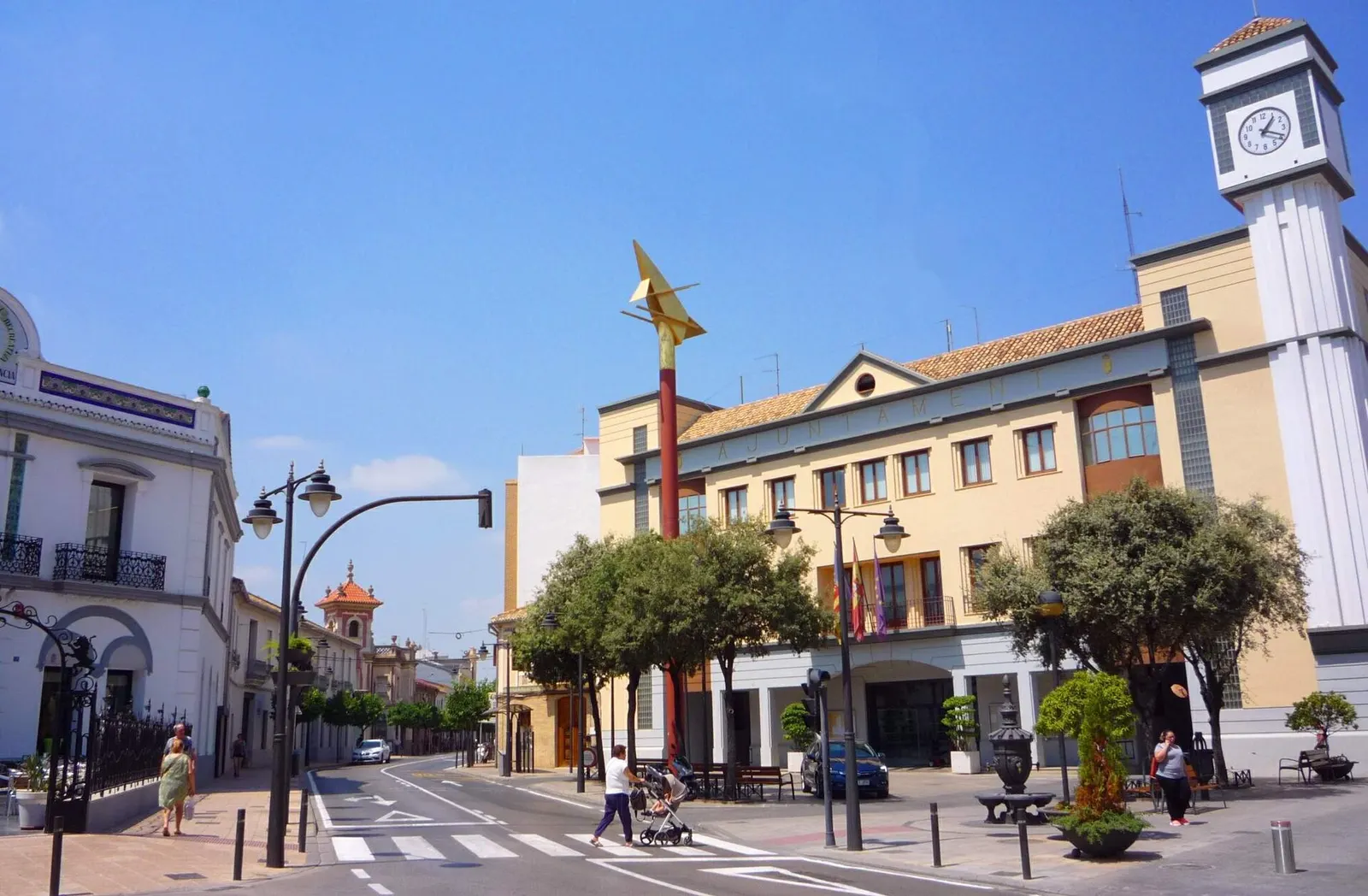 Ayuntamiento de Quart de Poblet, edificio de color crema con torre del reloj, junto a una calle con paso de peatones y árboles