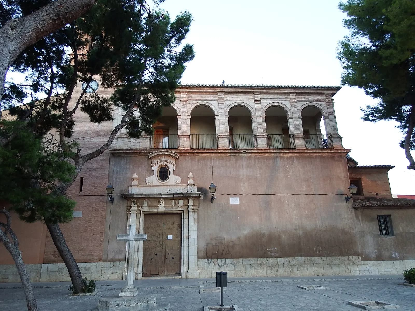 Iglesia de Sant Sebastià Màrtir de Rocafort, con galería de arcos y portada de piedra entre pinos