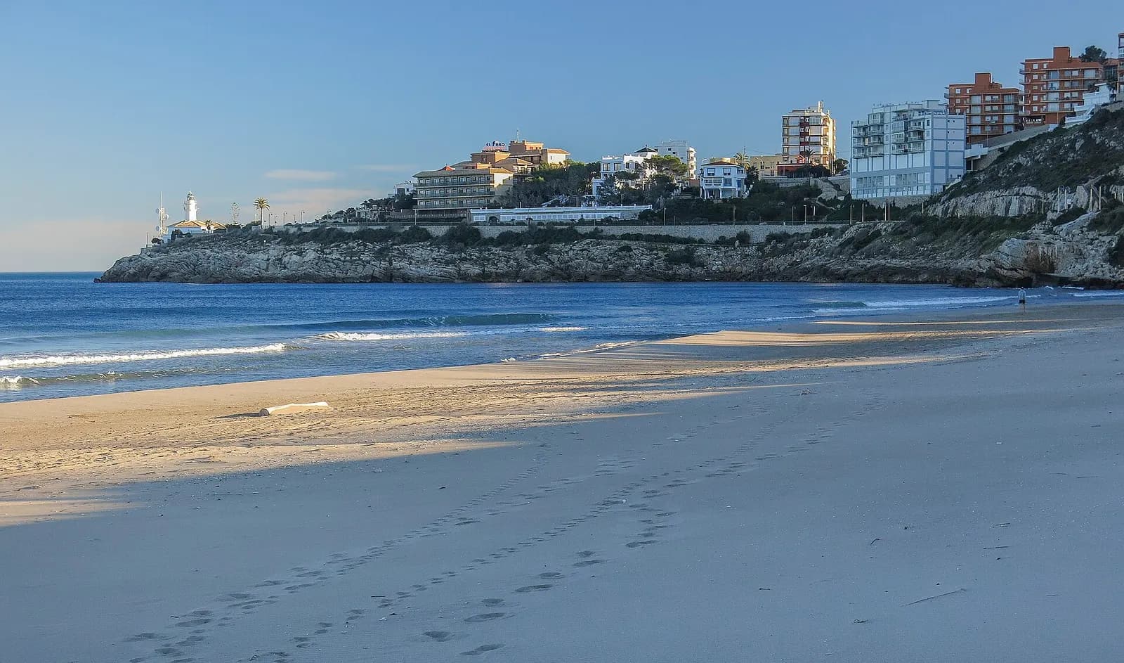 Playa del Dosser de Cullera con el faro y los edificios de apartamentos sobre el cabo