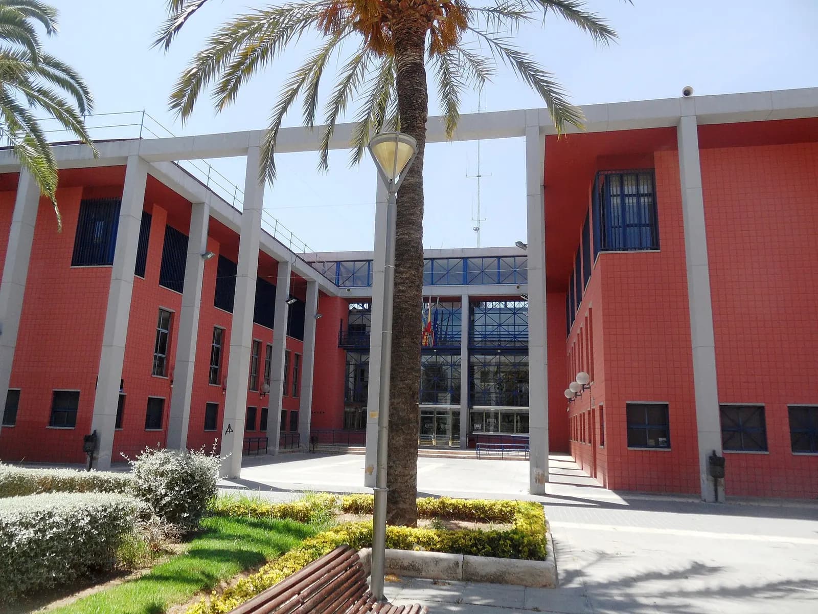 Ayuntamiento de Xirivella, edificio de ladrillo rojo con pórtico de pilares blancos y jardín con palmeras