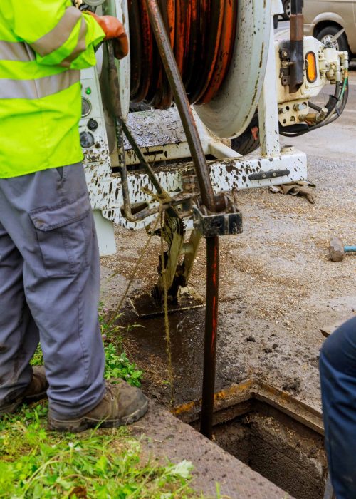 Sewage cleaning workers equipment with sewer on a town street on industrial truck
